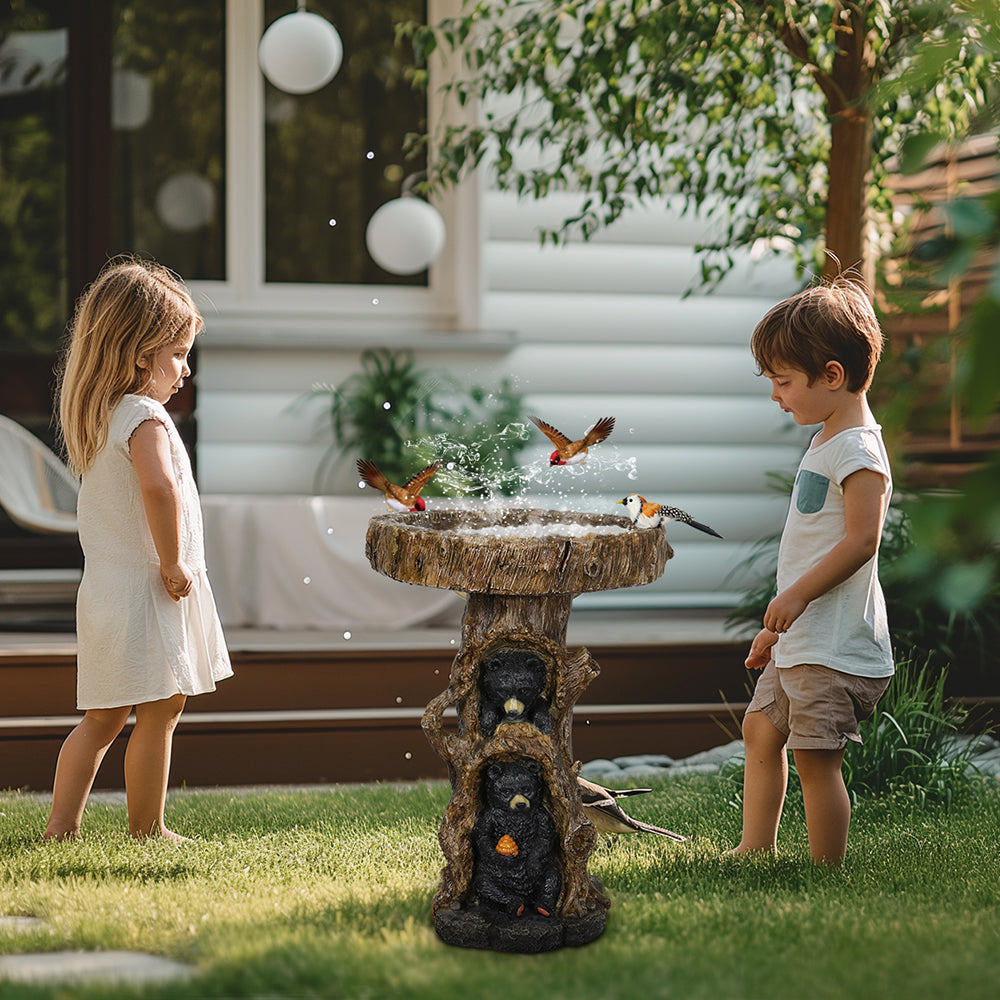 Children watching wild birds flutter around the charming black bear bird bath in a sunny backyard garden.