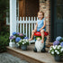 Child sitting happily on the whimsical gnome mushroom garden stool on a cozy front porch.