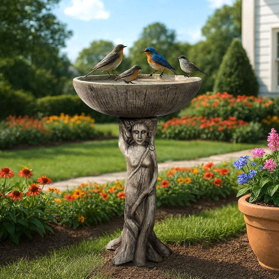 Classical goddess figurine concrete bird bath standing elegantly in a garden bed with colorful hydrangeas.