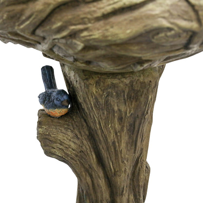 Close-up of the charming blue decorative faux bird on the tree trunk of the rustic birdbath.