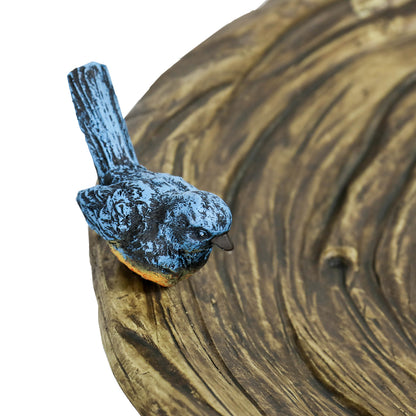 Close-up of the charming blue decorative faux bird perched on the edge of the leaf-textured birdbath bowl.