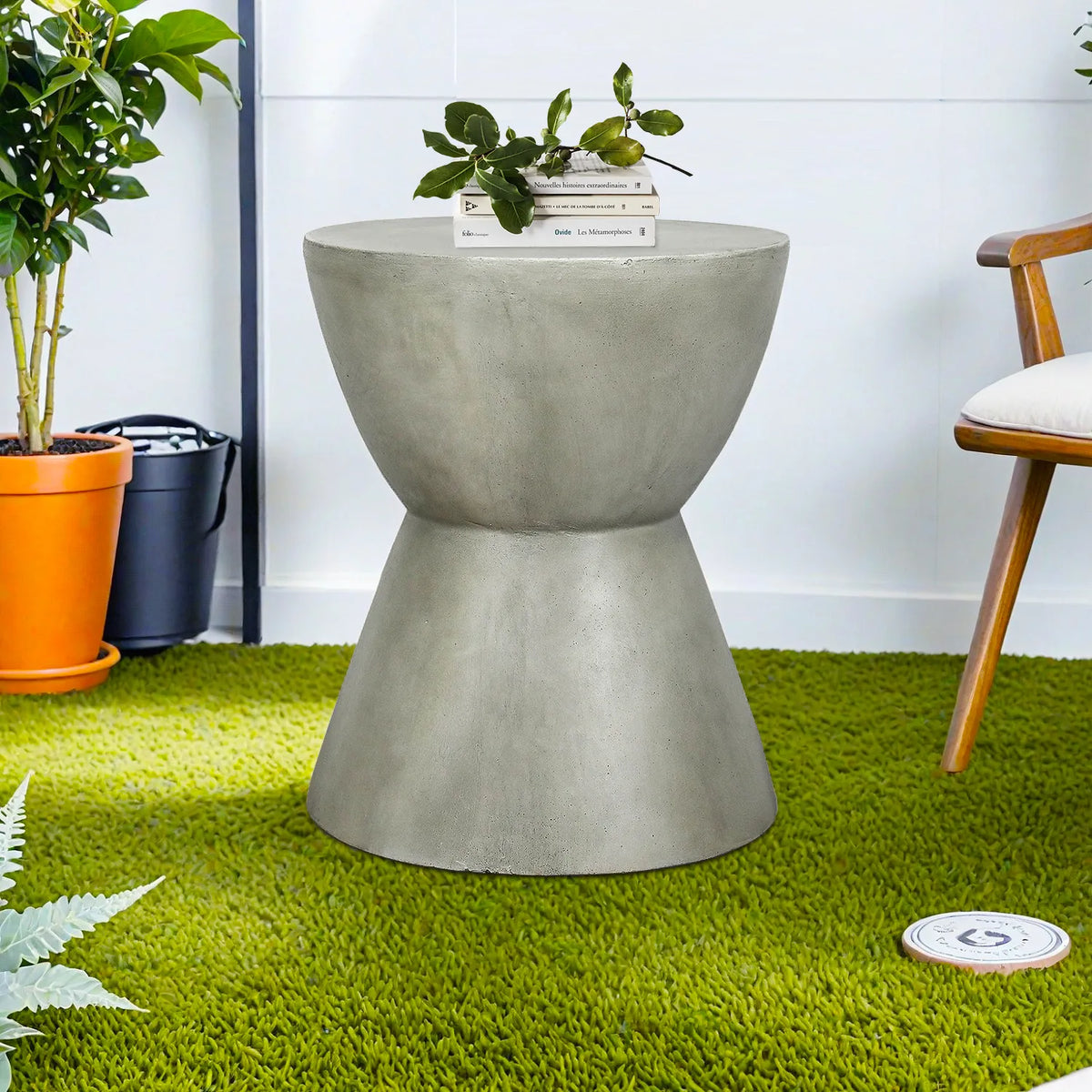 Grey concrete pedestal side table placed on a green lawn for outdoor patio decor.