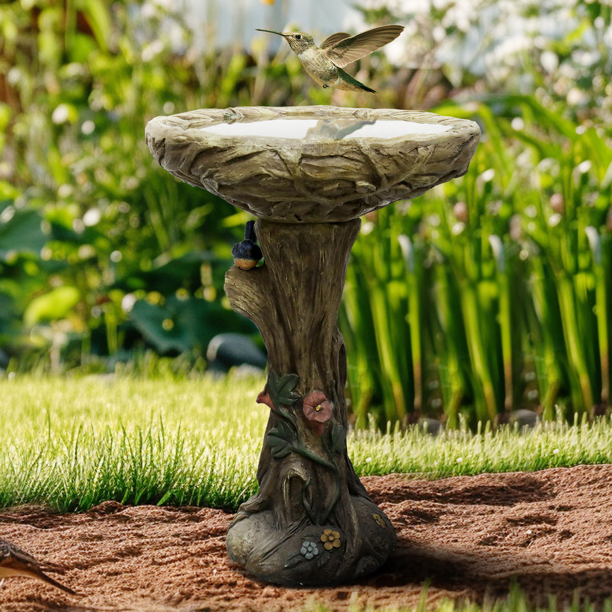 Rustic 25.5"H tree shape concrete birdbath serving as a beautiful centerpiece in a spring garden bed.