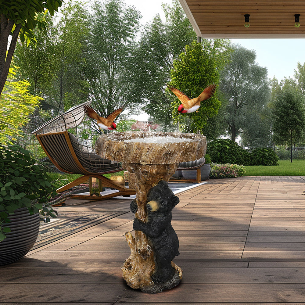 Rustic black bear bird bath decorating a paved outdoor patio area.