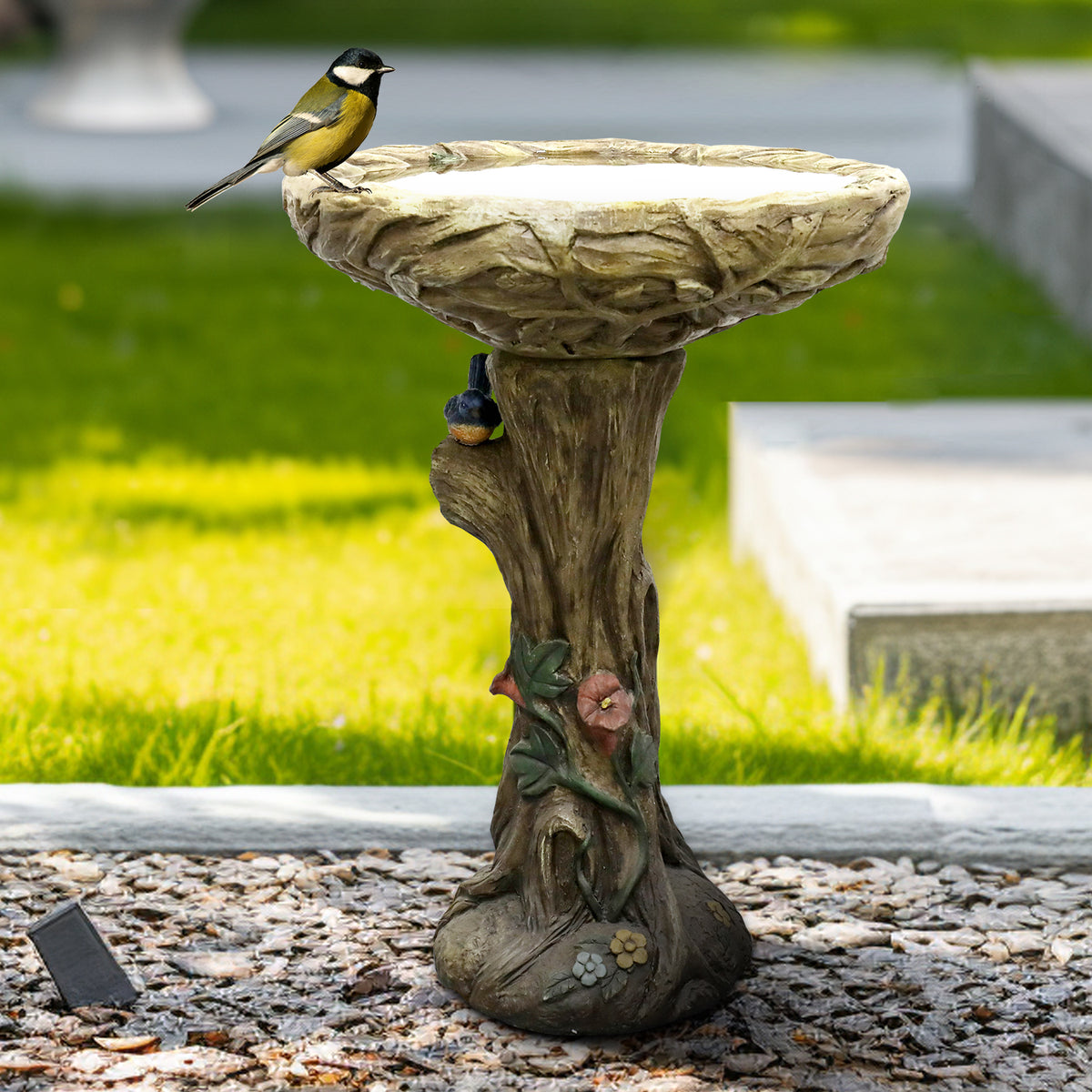 Rustic tree shape concrete birdbath providing a safe oasis for feathered friends in a lush backyard.