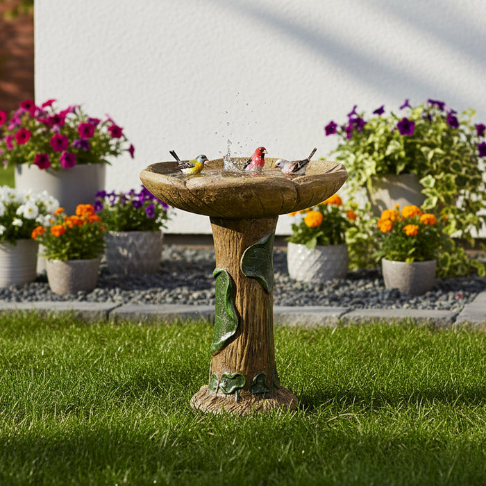 Rustic concrete bird bath beside a garden fence.