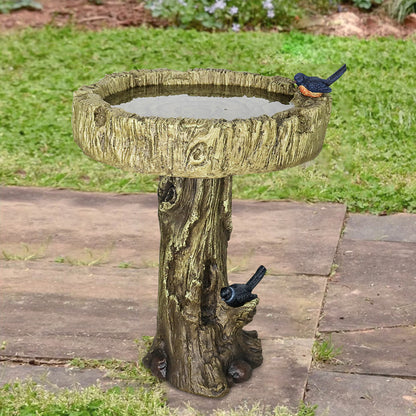 Tree trunk birdbath placed where the lawn meets the house wall.