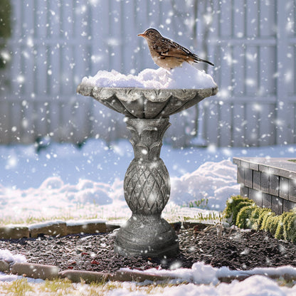 Weather-resistant 16.5kg concrete bird bath withstanding snow in a winter garden, attracting wild birds.