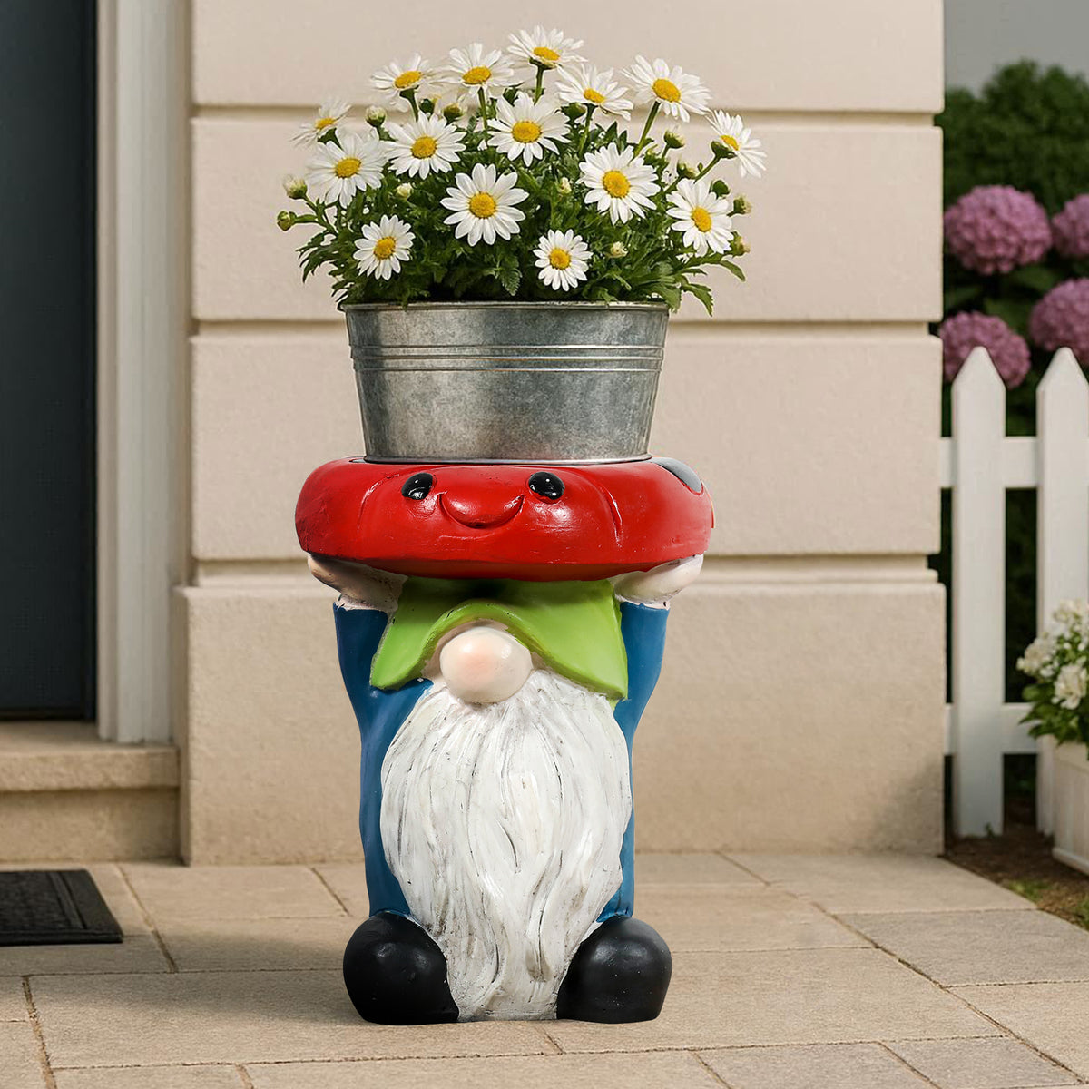Whimsical gnome statue used as a sturdy outdoor plant stand holding a pot of white daisies on a porch.